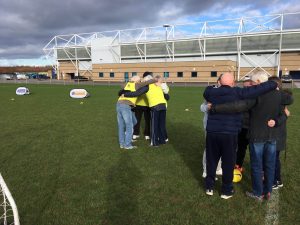 Kick Cancer participants huddle for a team talk before a football activity